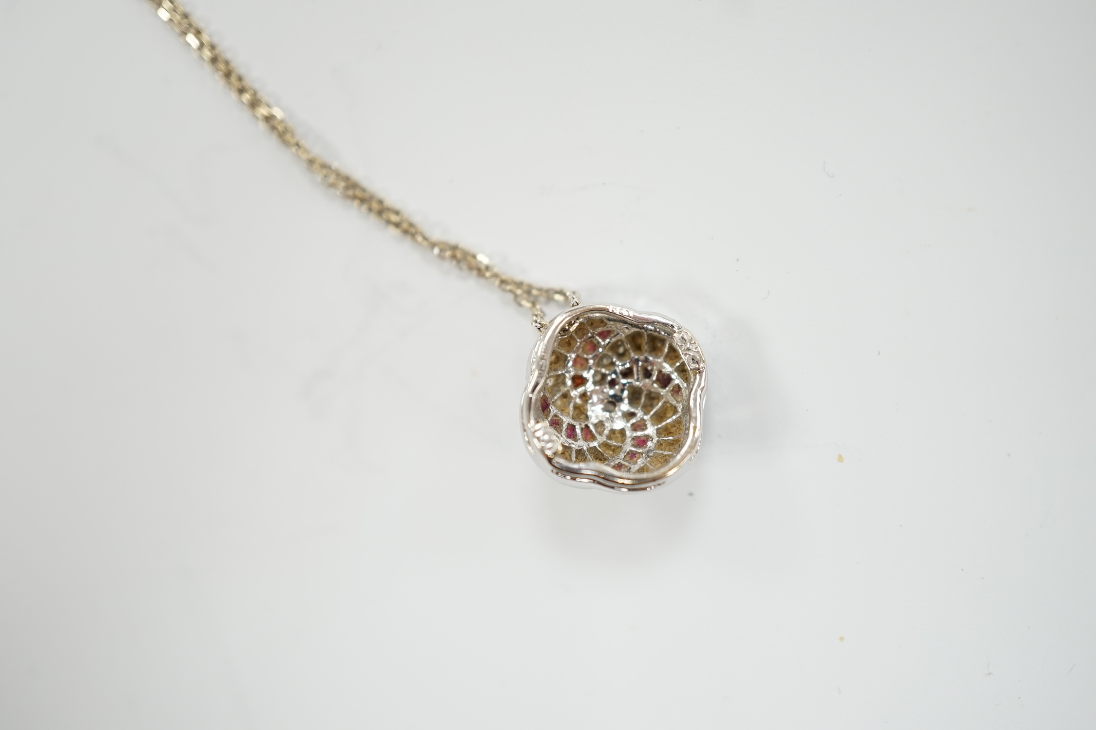 A modern 18ct white gold, ruby and diamond cluster set pendant, 14mm, on a 750 white metal fine link chain, 39cm, gross weight 3.4 grams.